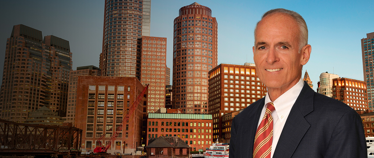 Thomas M. Greene in a suit with city skyline in the background.